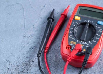 Red multimeter or a multitester, also known as a VOM on gray table. Electronic measuring instrument. Red and black wires