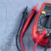 Red multimeter or a multitester, also known as a VOM on gray table. Electronic measuring instrument. Red and black wires